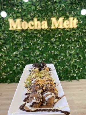 Triple Chocolate Lukma drizzled with chocolate and served in front of the Mocha Melt living wall